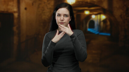Woman gestures timeout in ancient roman ruins with a focused expression, showcasing a blend of modern communication against a backdrop of historical architecture.