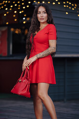 Sexy lady in red dress posing with bag