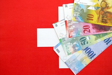 Swiss franc banknotes and flag. The current francs money bills lies on flag in big amount