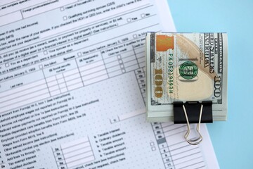 Big amount of United States hundred dollar bills on table with tax return form close up