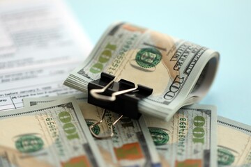 Big amount of United States dollar bills on table with tax return form close up