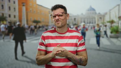 Young man with glasses in vatican city square wearing red striped shirt with people and urban...
