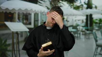 Priest standing on a terrace, wearing a clerical robe and cross, holding a bible, exuding serenity,...