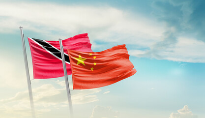 Trinidad and Tobago and China flags waving in beautiful sky. Two country flag for agreement or...