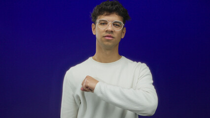 Man with silverframe glasses wearing a ribbed long sleeve shirt shows a clenched fist forward in...