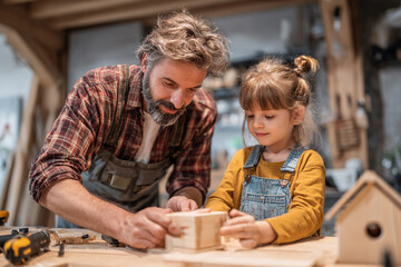 Father helping daughter build birdhouse
