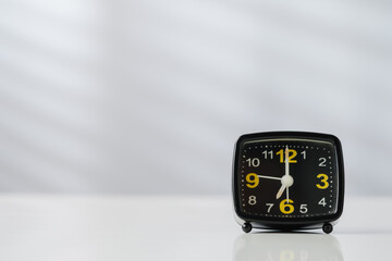 Black Alarm Clock with Yellow Numbers on White Background with copy space.