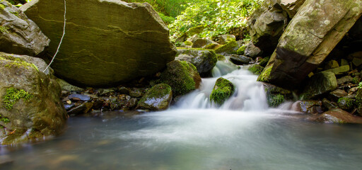 A stream of water flows between large rocks