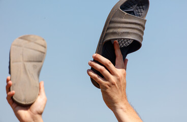 A person is holding a pair of sandals in their hands