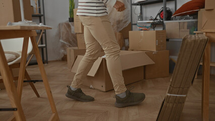 Fototapeta premium Hispanic man organizing boxes in a new home interior with visible furniture and accessories suggesting moving activities and unpacking in the living room.