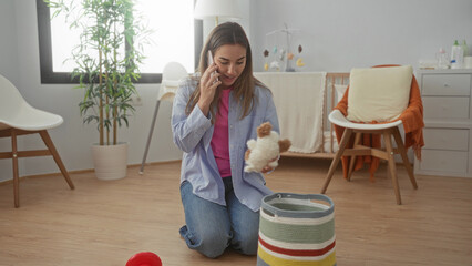 Woman talking on phone while organizing toys in a cozy baby room, showcasing a modern interior with natural light and soft decor elements for home lifestyle imagery.