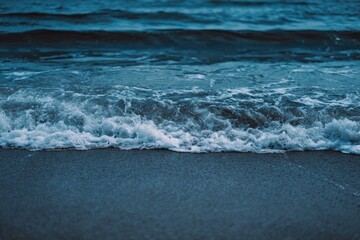 Fototapeta premium Ocean waves crashing on a beach at dusk