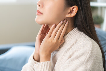 Sickness in inflaming asian young woman, girl use hand check self touch at sore throat, pain thyroid gland on neck or disease reflux, acid of suffer people at home. Medical and healthcare.