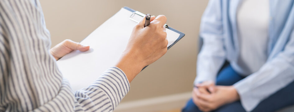 Psychology, depression. Suffer asian young woman consultation with psychologist while patient counseling mental therapy, doctor hand taking notes at clinic. Psychologist with sick mental health person