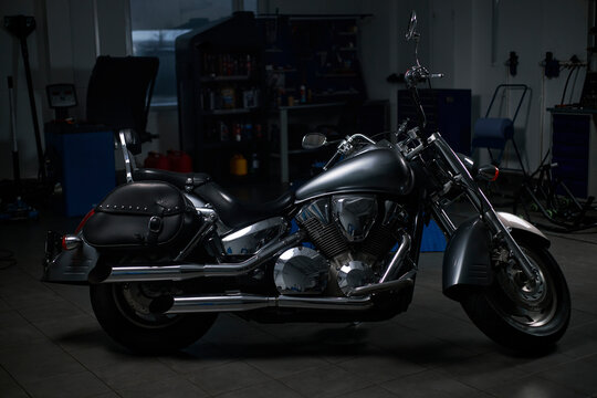 Chrome motorcycle parked in workshop garage with copy space