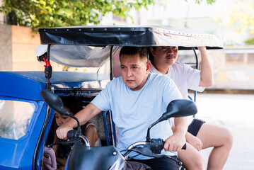 Southeast Asian driver keeps his eyes on the street while transporting passengers, showing a...
