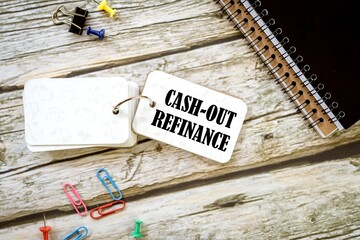 Cash-Out Refinance words on a small notebook. a beautiful wooden table. a pile of notebooks.