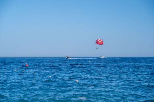 Parasailing Adventure Above Clear Blue Waters Near a Beach Under a Bright Sky With Boats Nearby