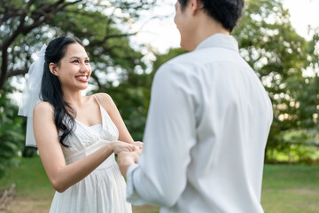 Fototapeta premium Asian romantic married couple looking each other in park during sunset. 