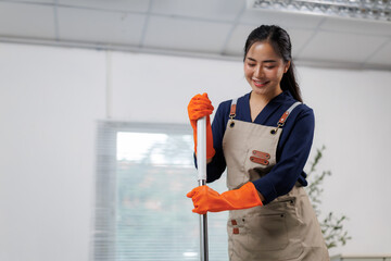 Young janitor smiling and holding a mop in the office