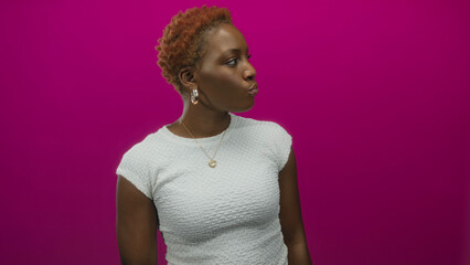African american woman turning head with pursed lips against magenta studio wall to show lips;...