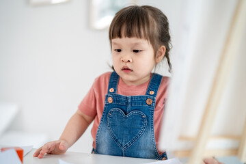 Asian young baby girl enjoy painting on paper in living room at home