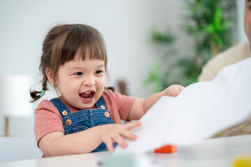 Asian young baby girl enjoy painting on paper in living room at home. 