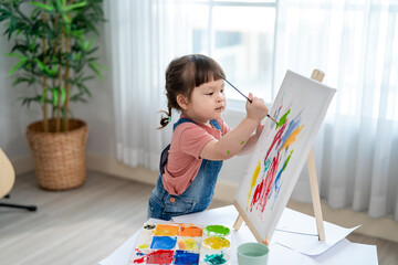 Asian young baby girl enjoy painting on a board in living room at home. 