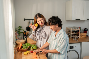 Asian transgender woman and her male partner cooking foods in house.