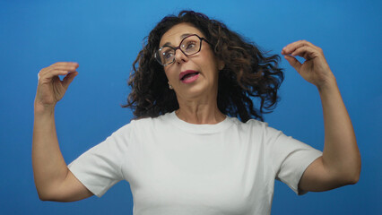 Middle aged hispanic woman gesturing with arms and hands in a studio setting; communication expression engagement conversation.