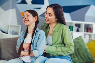 Mother and daughter sharing a loving moment on the couch, expressing happiness and family bonding...