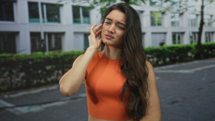 Woman pressing cheek with hand for toothache on a busy city street on concrete pavement; discomfort.