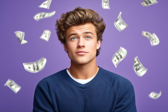 Young man gazes upward with a thoughtful expression as dollar bills float around him. Purple backdrop enhances the energetic vibe. Concept of finance, wealth, entrepreneurship