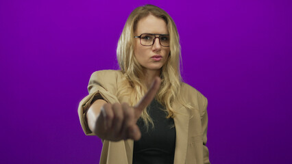 Woman gestures no with finger wearing glasses and blazer against vivid purple background...