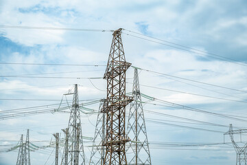 High voltage transmission power towers against a cloudy sky.