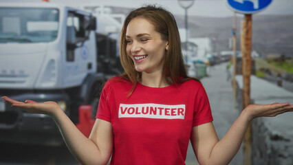 Woman wearing volunteer tshirt showing palms up gesture and smiling face on city street; compassion...