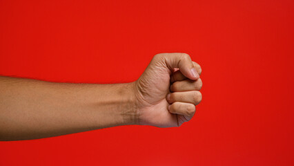 Man's clenched fist against a vibrant red background showcasing determination and strength, with...
