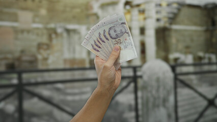 Man displaying singapore dollars outdoors with a city backdrop, highlighting currency handling in a...