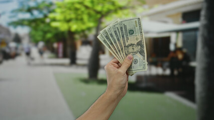 Man holding united states dollars in the street with blurred cityscape background, showcasing...