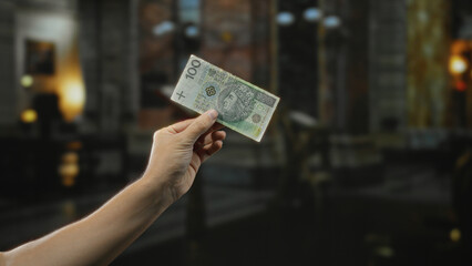 Man holding polish zloty banknote indoors in church, capturing the interplay of personal finance...
