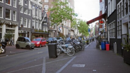 Amsterdam city scene with defocused urban street, rows of bikes, parked cars, and traditional...
