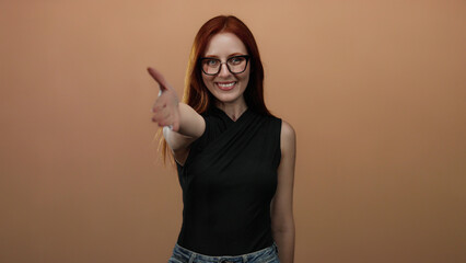 Woman smiling with outstretched hand in a friendly greeting against a simple brown background...