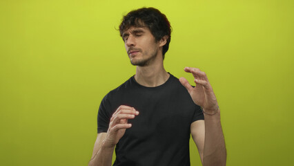 Man wearing black t shirt with expectant pose and raised hands in bright lime green studio; tension.