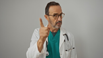 Doctor pointing intensely at the camera wearing glasses and a stethoscope against a plain white...