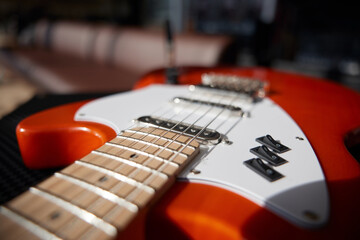An orange electric guitar on top of a powerful amplifier