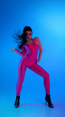 Dancer in pink bodysuit and high heels striking a pose under blue lighting. Concept of energy in...