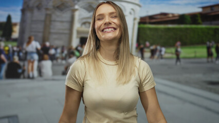 Woman smiling outdoors in front of pisa tower making a gesture while surrounded by a crowd on a...