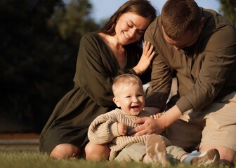 happy loving family with baby son sitting on grass in park