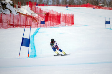 alpine skier racing downhill on snowy ski slope during giant slalom competition