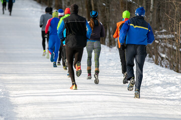 mixed group runners in winter outdoor race or marathon on snow-covered trail